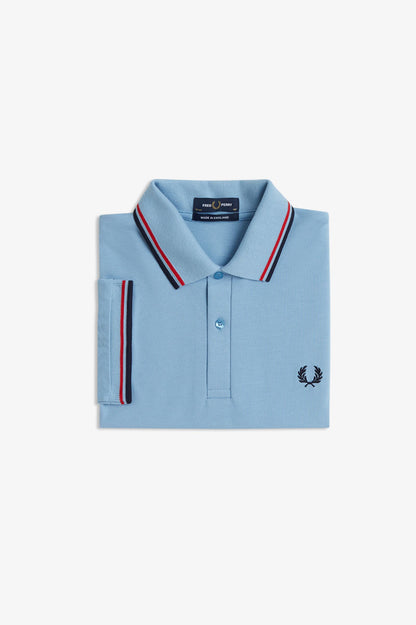 Light blue polo shirt with red and navy striped trim on a white background