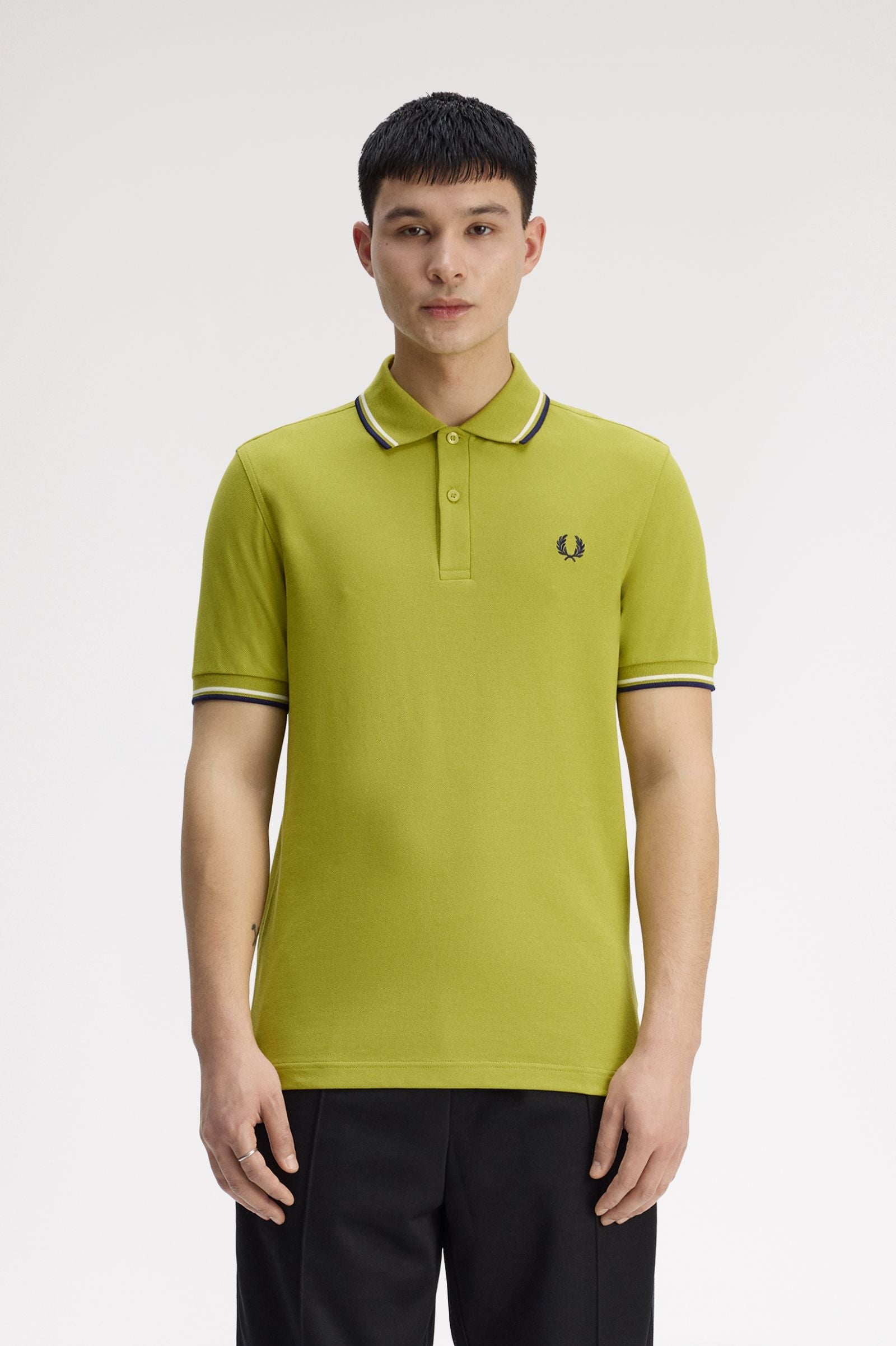 Man wearing a green polo shirt with a brand logo on a white background