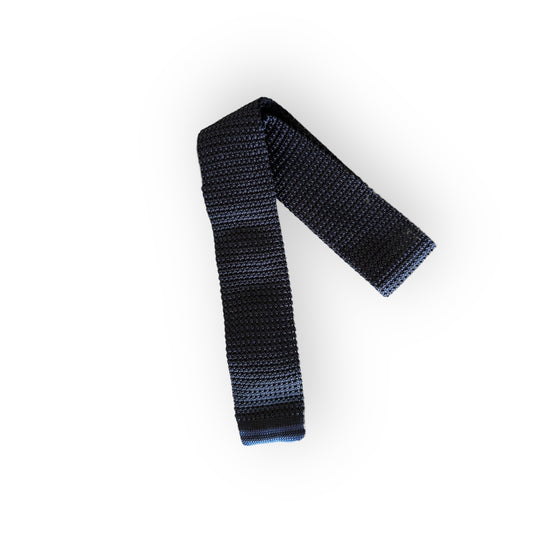 A navy plain silk knitted tie against a white background.