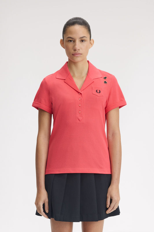 Woman wearing a coral polo shirt with a brand logo on a white background
