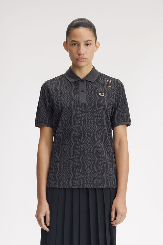 Person wearing a patterned black polo shirt with a visible brand logo on a white background