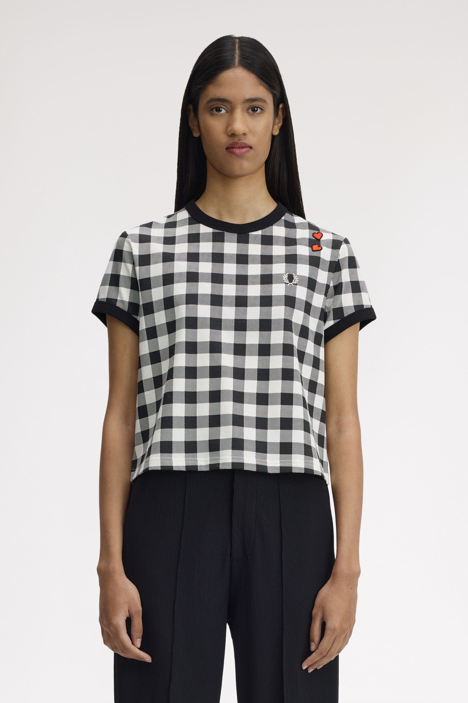 Person wearing a black and white checkered t-shirt with a brand logo on a plain background