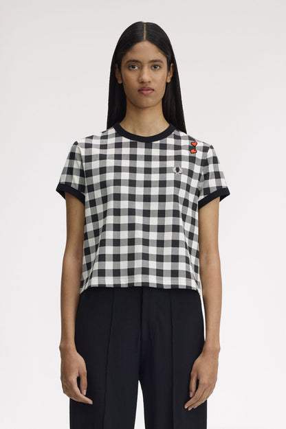 Person wearing a black and white checkered t-shirt with a brand logo on a plain background