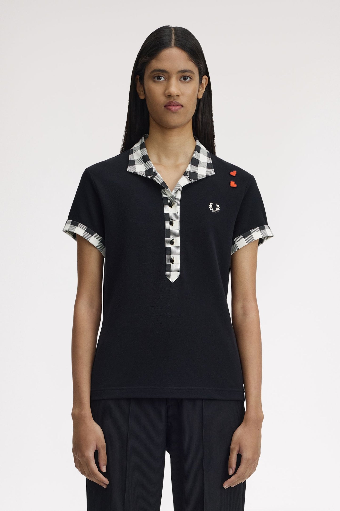 Person wearing a black polo shirt with checkered collar and brand logo on a white background
