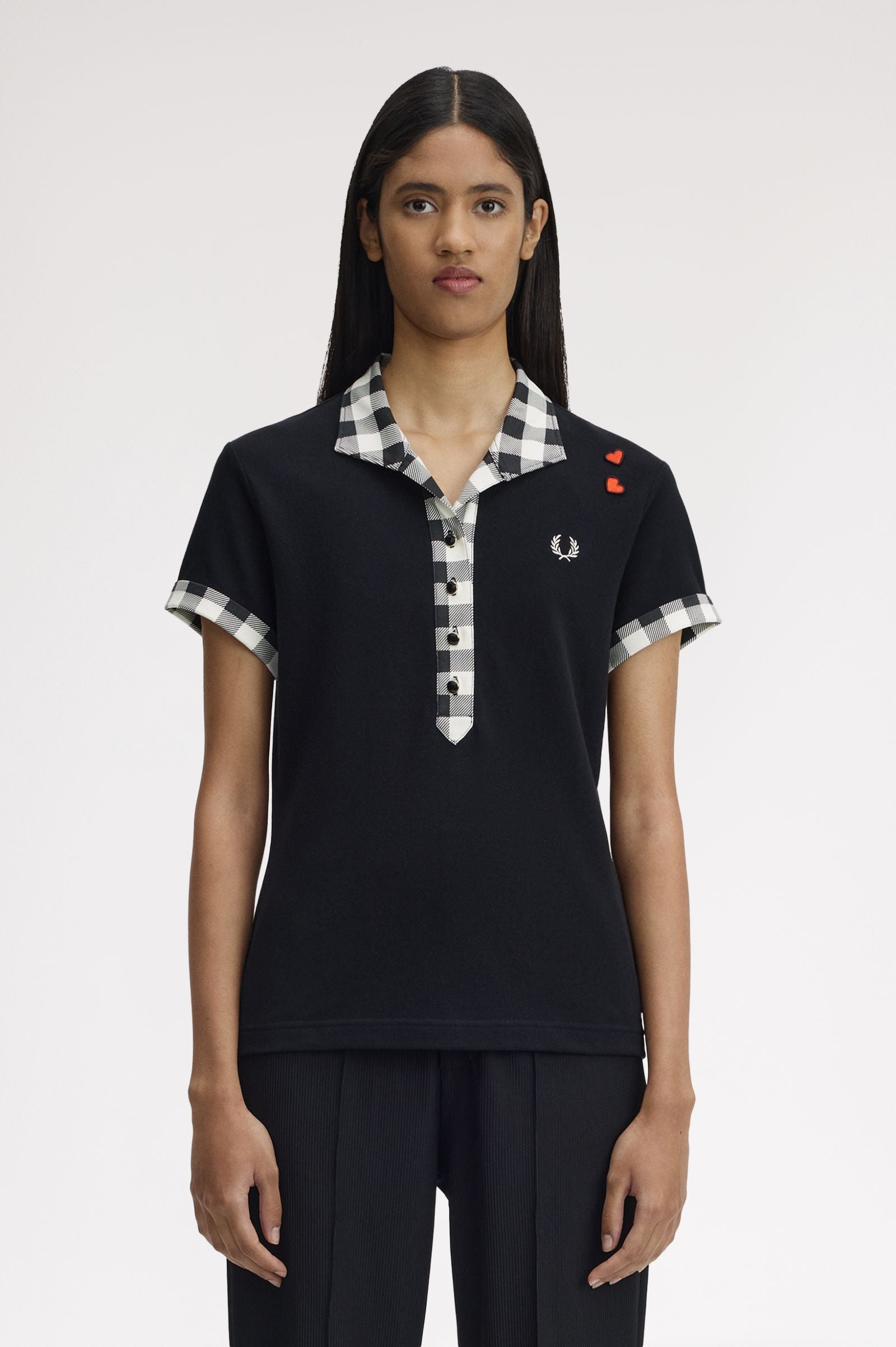 Person wearing a black polo shirt with checkered collar and brand logo on a white background