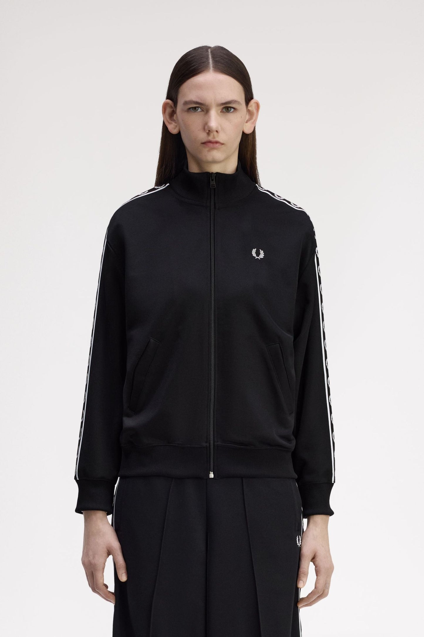 Person wearing a black tracksuit with a brand logo on a white background