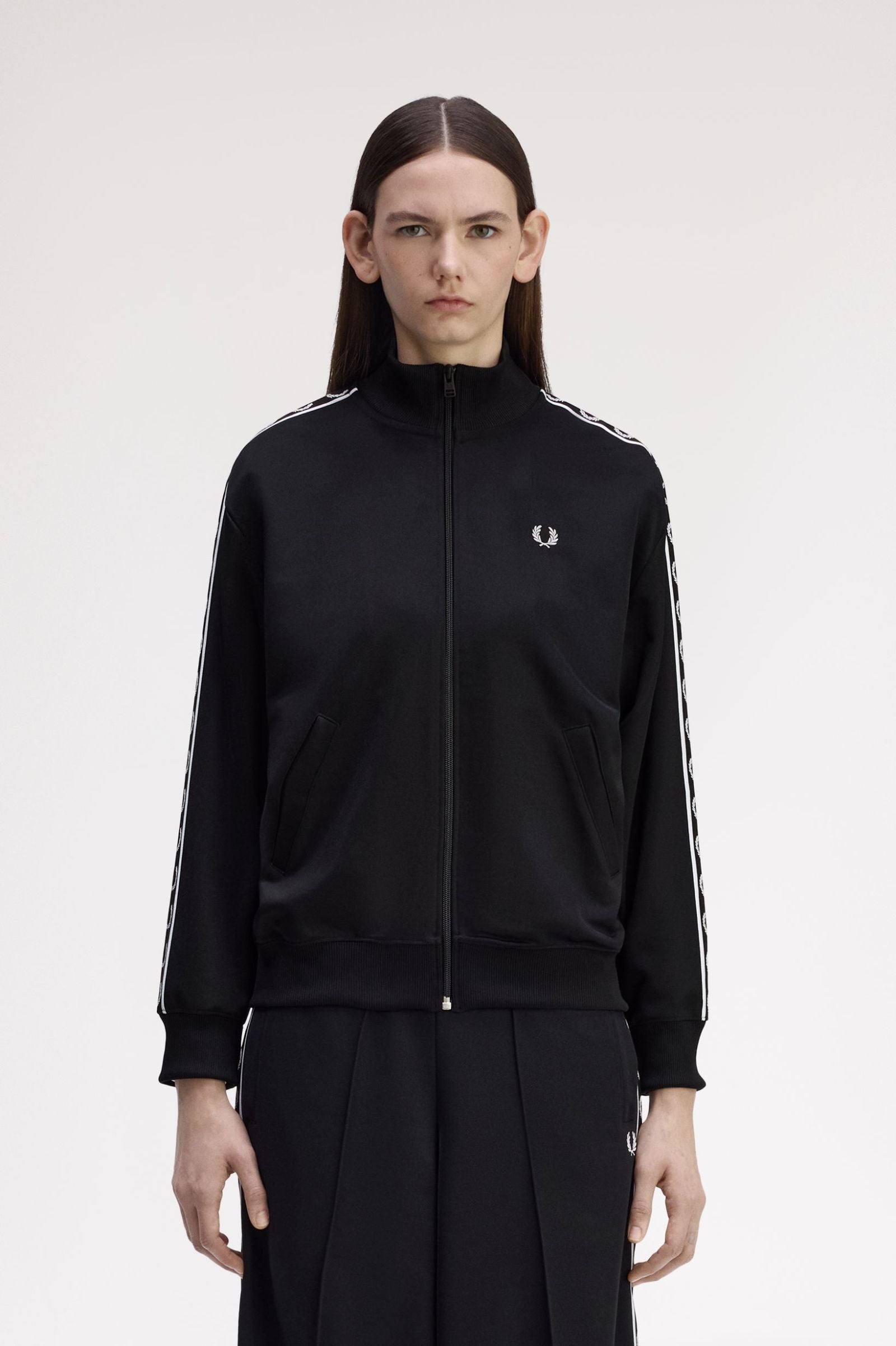 Person wearing a black tracksuit with a brand logo on a white background