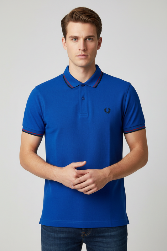 Man wearing a blue polo shirt with a brand logo on a light gray background