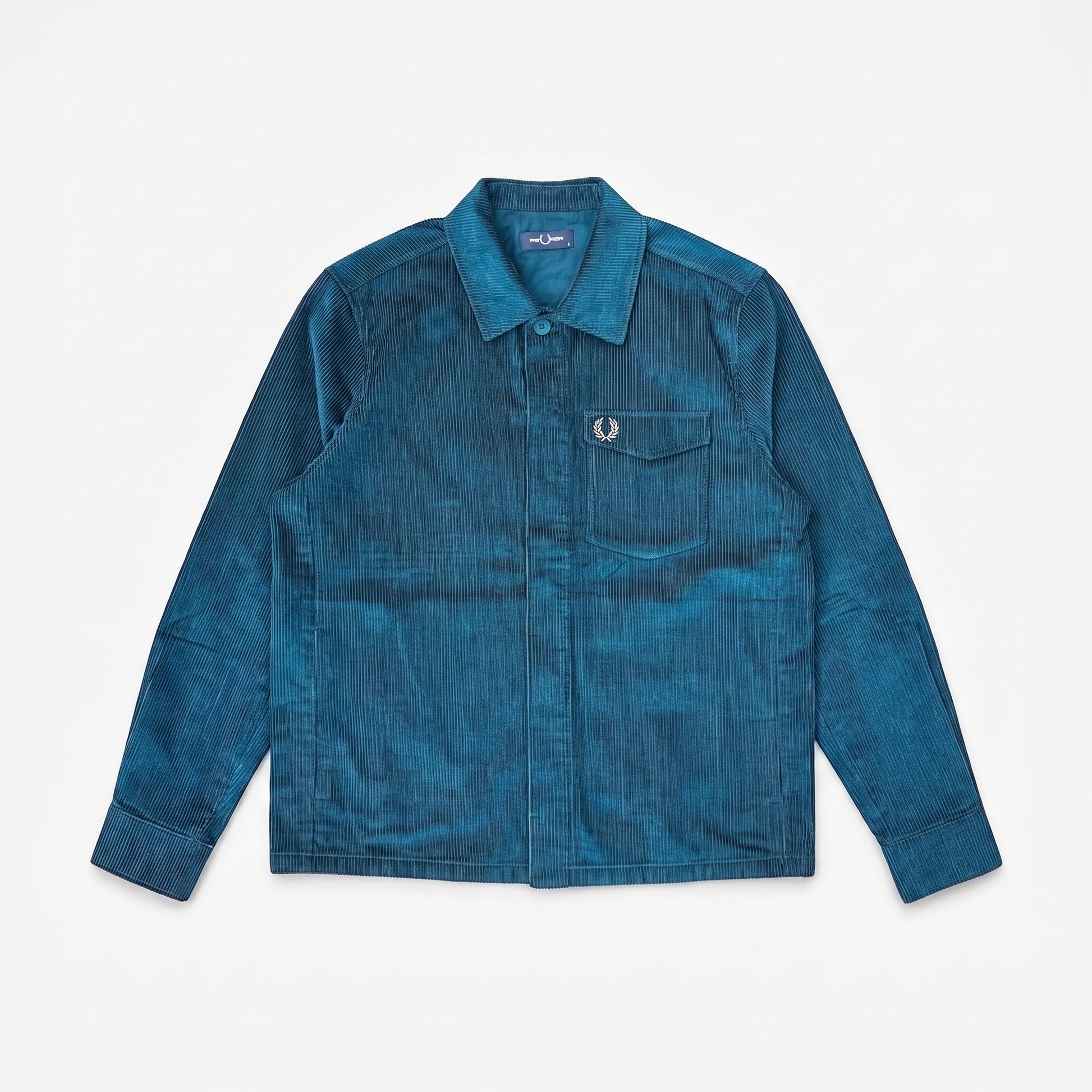 A blue corduroy button-up shirt jacket by Fred Perry, featuring a chest pocket with the signature laurel wreath logo, laid flat against a white background.