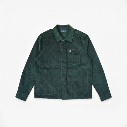A dark green corduroy utility shirt jacket with a pointed collar, button-up front, and a chest pocket featuring a signature Fred Perry laurel wreath emblem, laid flat on a white background.