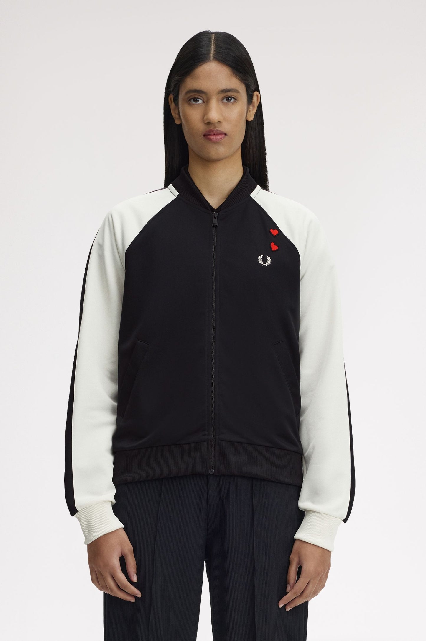 Person wearing a black and white jacket with a red logo on a white background