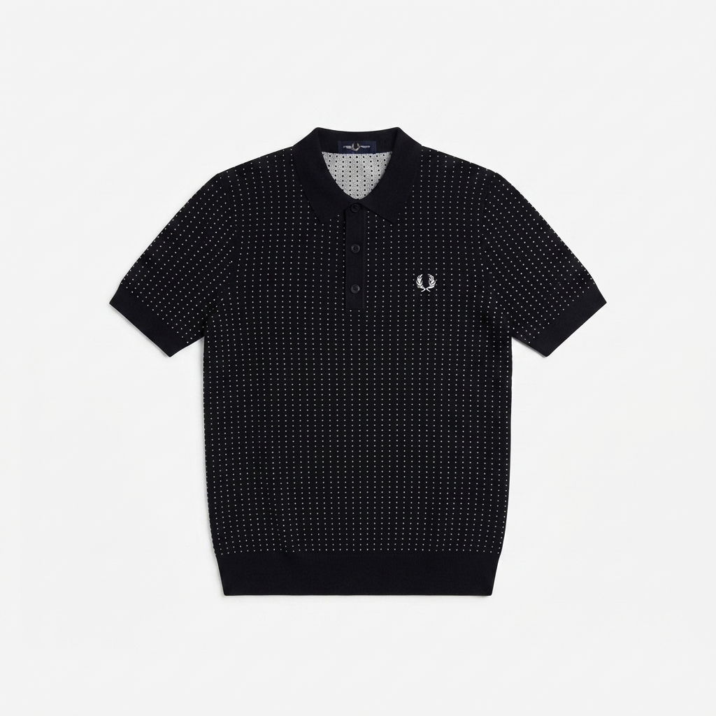 A short-sleeve polo shirt by Fred Perry featuring a black and white micro-dot pattern, a classic collar, and the signature embroidered laurel wreath logo on the left chest, displayed flat against a light gray background.