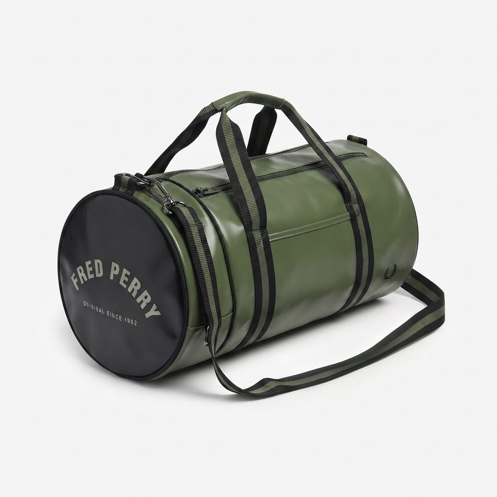 An olive green cylindrical duffel bag with black straps and a black circular end cap featuring the white 'FRED PERRY' logo, shown on a light gray background.