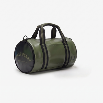 An olive green cylindrical duffel bag by Fred Perry, featuring black webbing handles, black side stripes, and a black circular end cap with gold lettering, set against a plain white background.