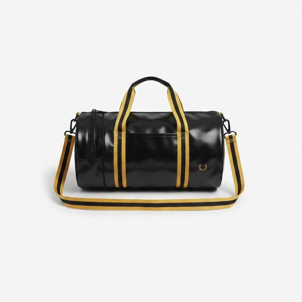 A black cylindrical duffel bag with gold and black striped handles and shoulder strap, featuring a gold-tone logo on the front, set against a light gray background.