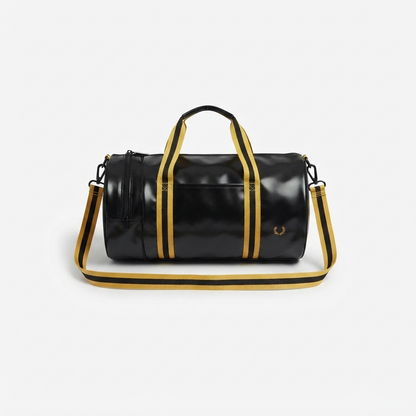A black cylindrical duffel bag with gold and black striped handles and shoulder strap, featuring a gold-tone logo on the front, set against a light gray background.