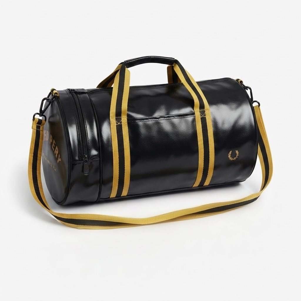A black vinyl duffel bag with gold trim, featuring dual top handles, a detachable gold-and-black shoulder strap, and gold branding details on a light gray background.