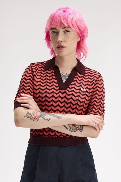 Person with pink hair wearing a red and black patterned shirt on a white background