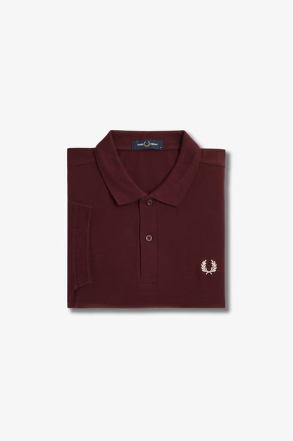Folded burgundy polo shirt with a brand logo on a light gray background