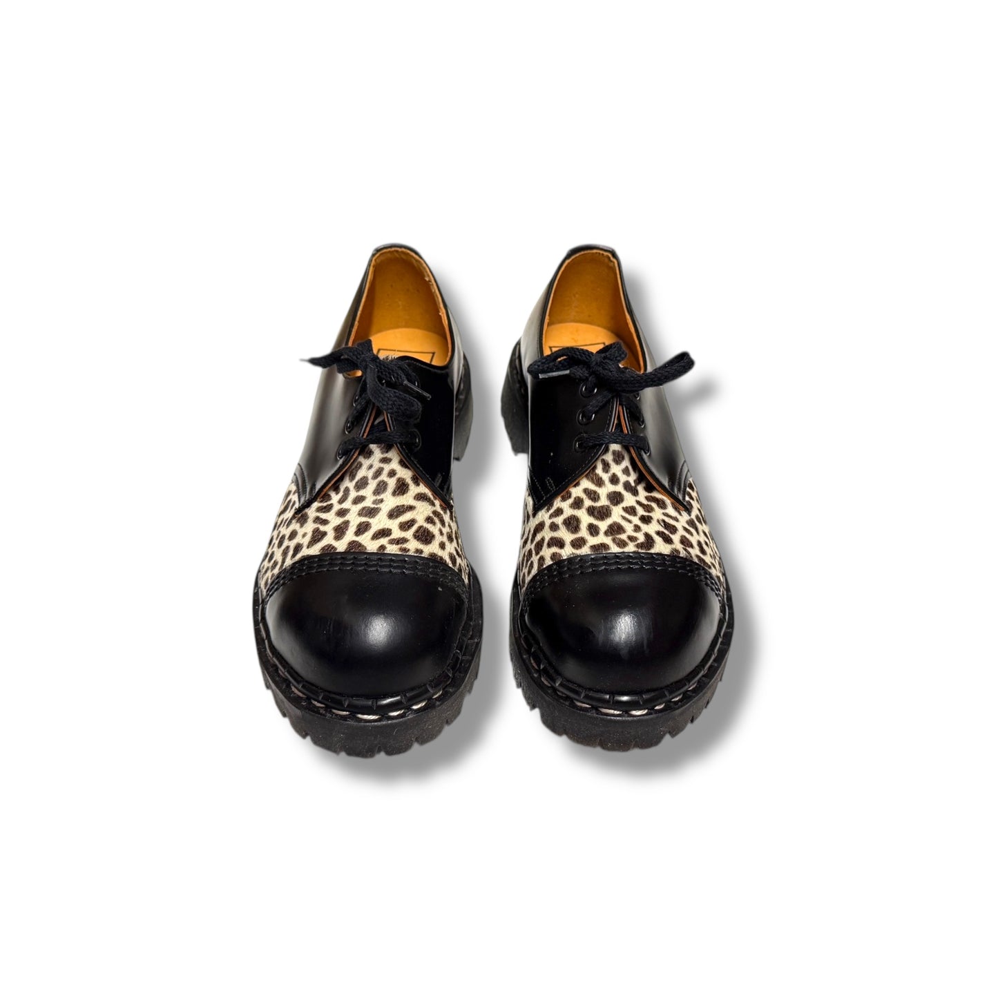Pair of black shoes with leopard print soles on a white background