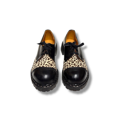 Pair of black shoes with leopard print soles on a white background
