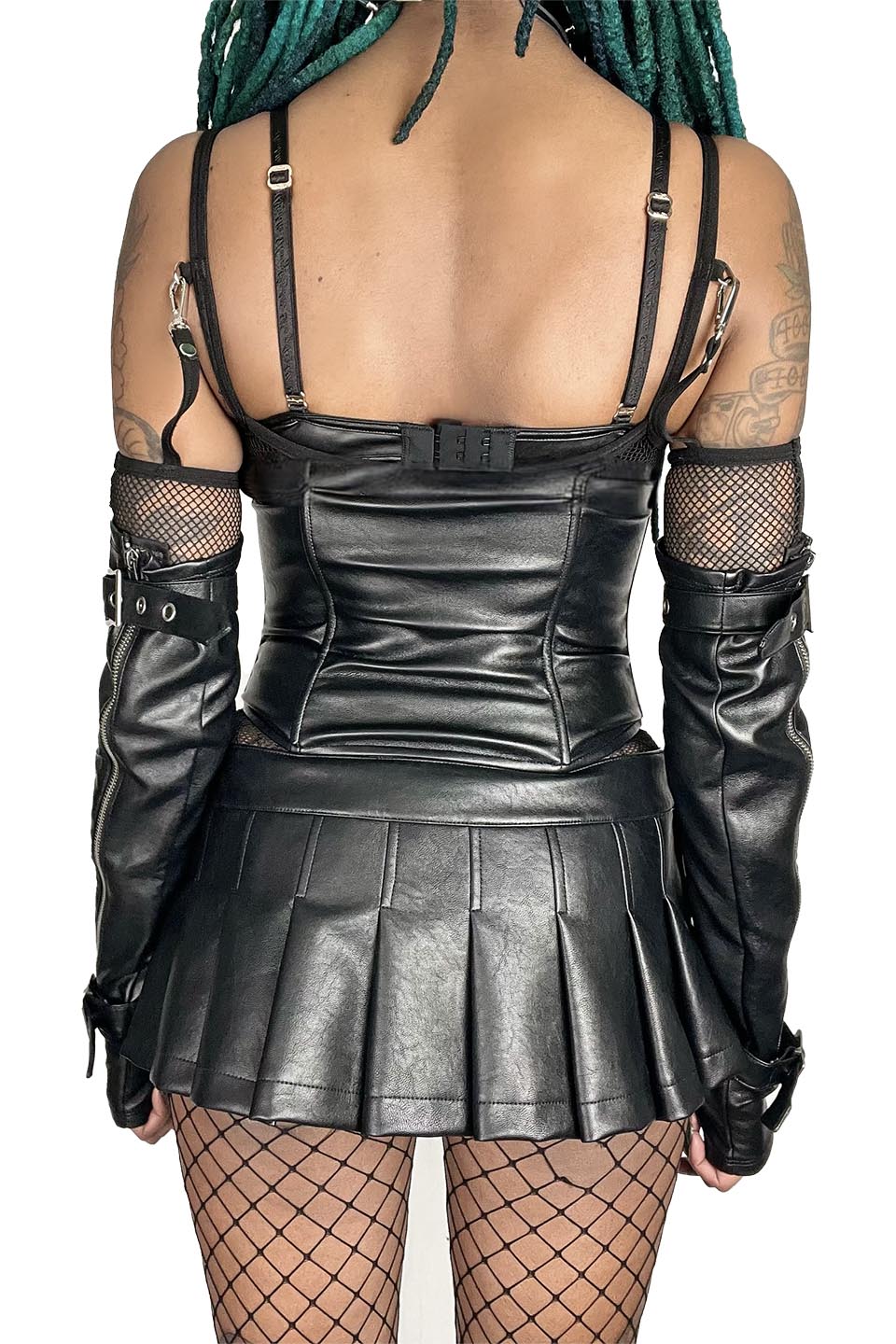 Person wearing a lip service black leather outfit with a pleated skirt on a white background