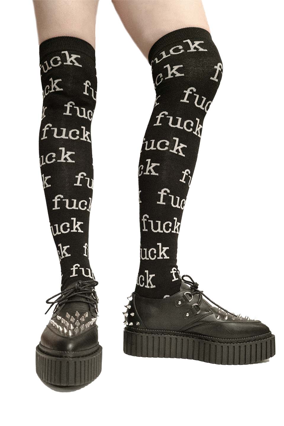 Lip service black knee-high socks with repeated text worn with black shoes on a white background