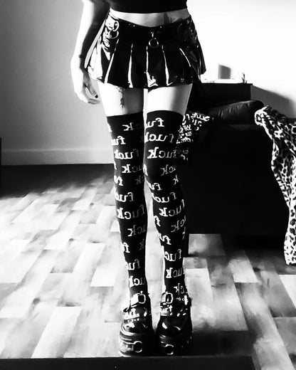 Person wearing lip service black knee-high socks with white patterns in a room.
