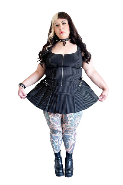 Person wearing a lip service  black pleated outfit with floral leggings on a white background
