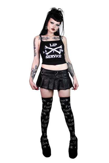 Person wearing a lip service  black tank top with text, black skirt, and black stockings with text on a white background