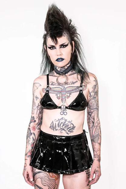 Person wearing a lip service  black vinyl outfit with tattoos on a white background