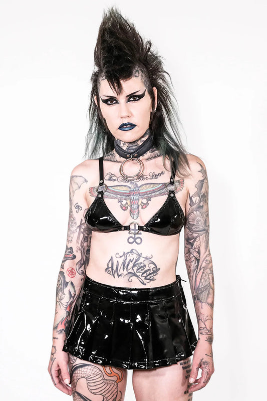 Person wearing a black vinyl outfit with tattoos on a white background