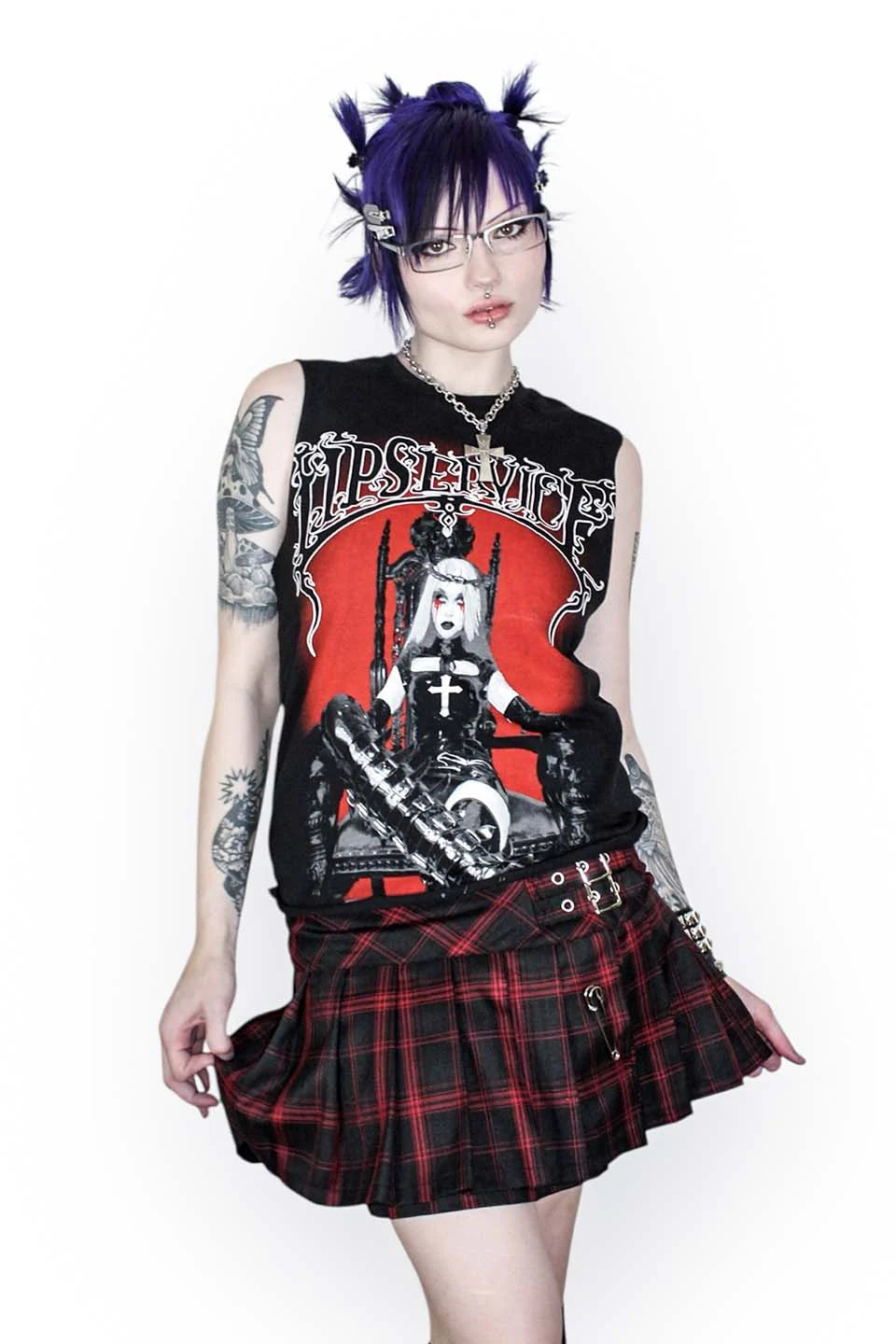Person wearing a graphic sleeveless top and lip service plaid skirt with a white background