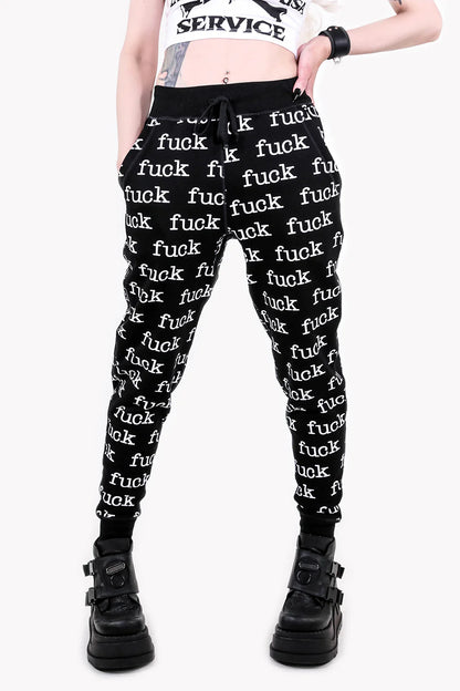Person wearing lip service black pants with 'fuck' text and black boots on a white background