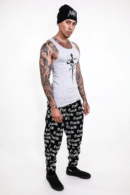 Person wearing a white tank top,lip service black pants with text, and a black beanie on a white background