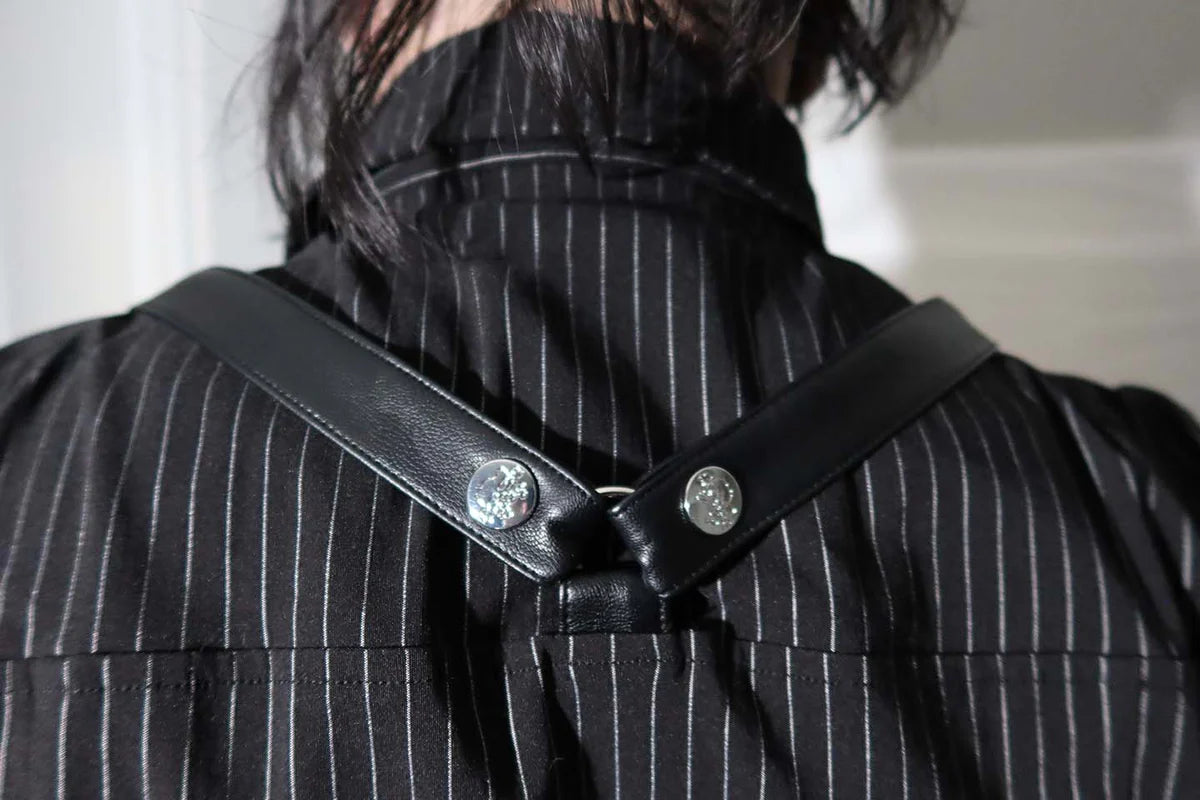 Close-up of a person wearing a lip service black pinstripe garment with a strap over their shoulder.