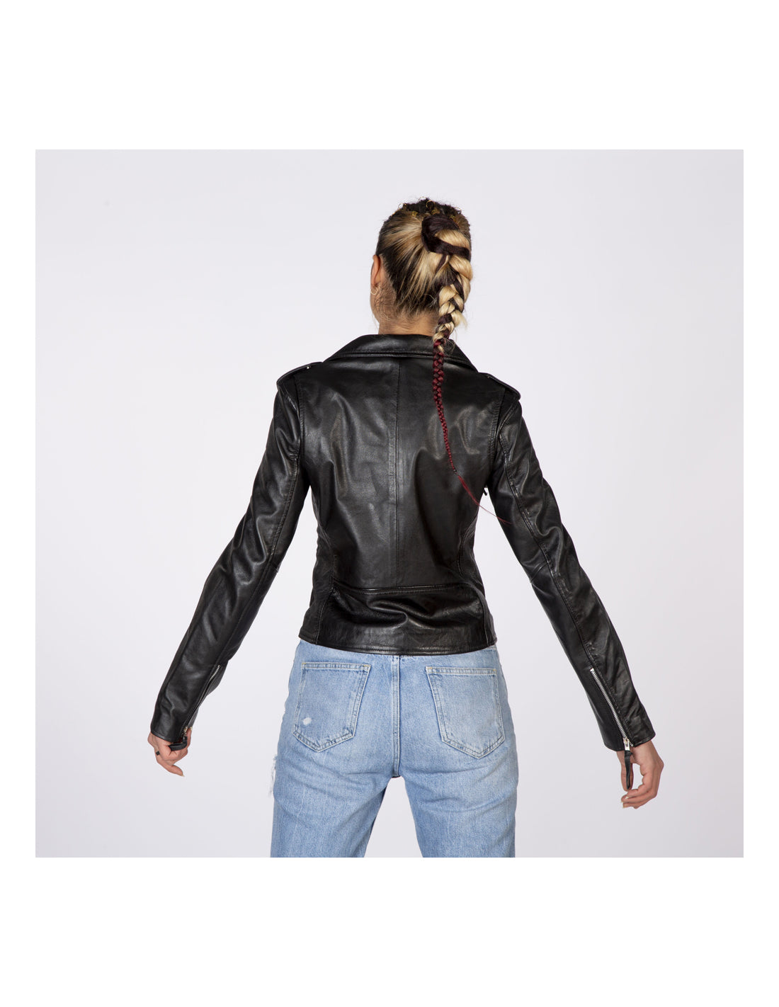Person wearing a black leather jacket and blue jeans on a white background