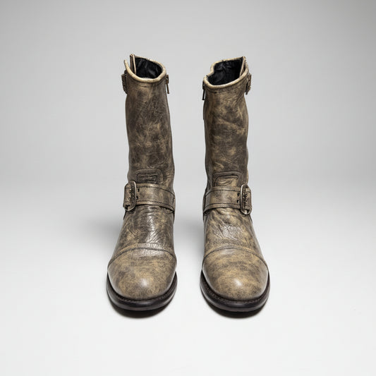 Pair of worn leather boots with buckles on a white background