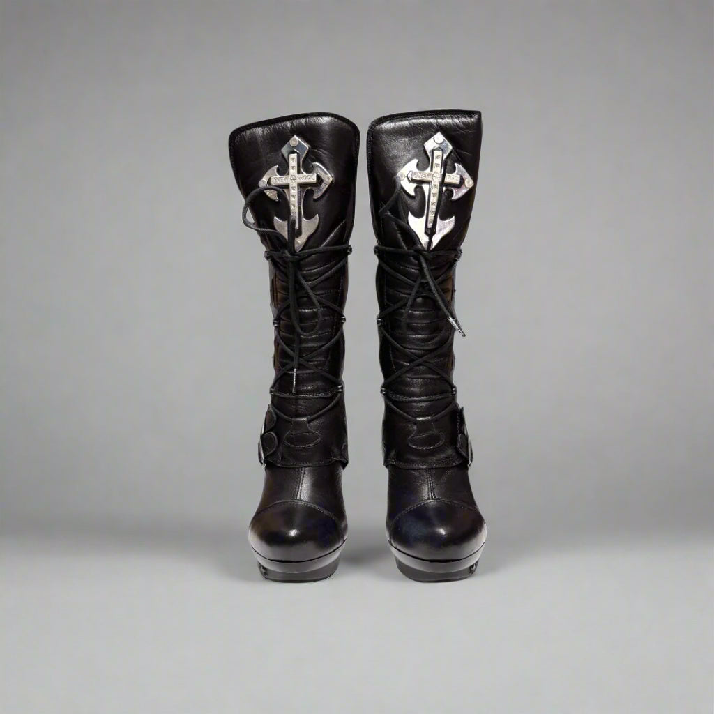 Pair of black knee-high boots with decorative crosses on a gray background