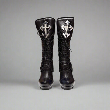 Pair of black knee-high boots with decorative crosses on a gray background