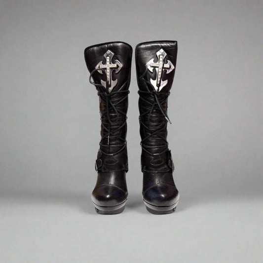 Pair of black knee-high boots with decorative crosses on a gray background