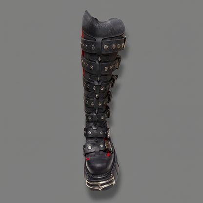 Black knee-high boot with metallic accents and red accents on a white background