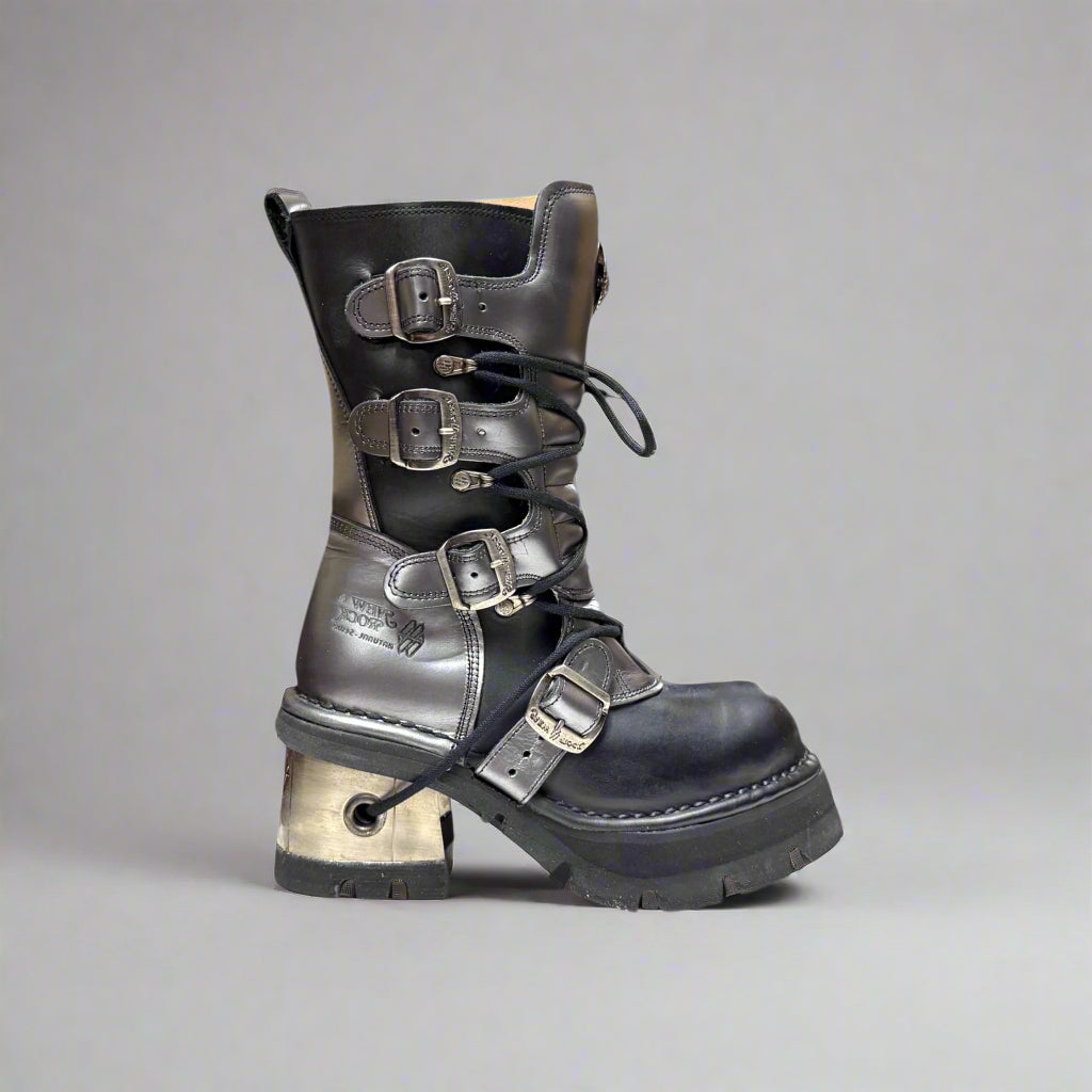 Black leather boot with metal buckles on a gray background