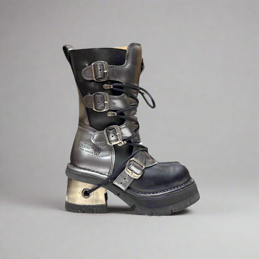 Black leather boot with metal buckles on a gray background
