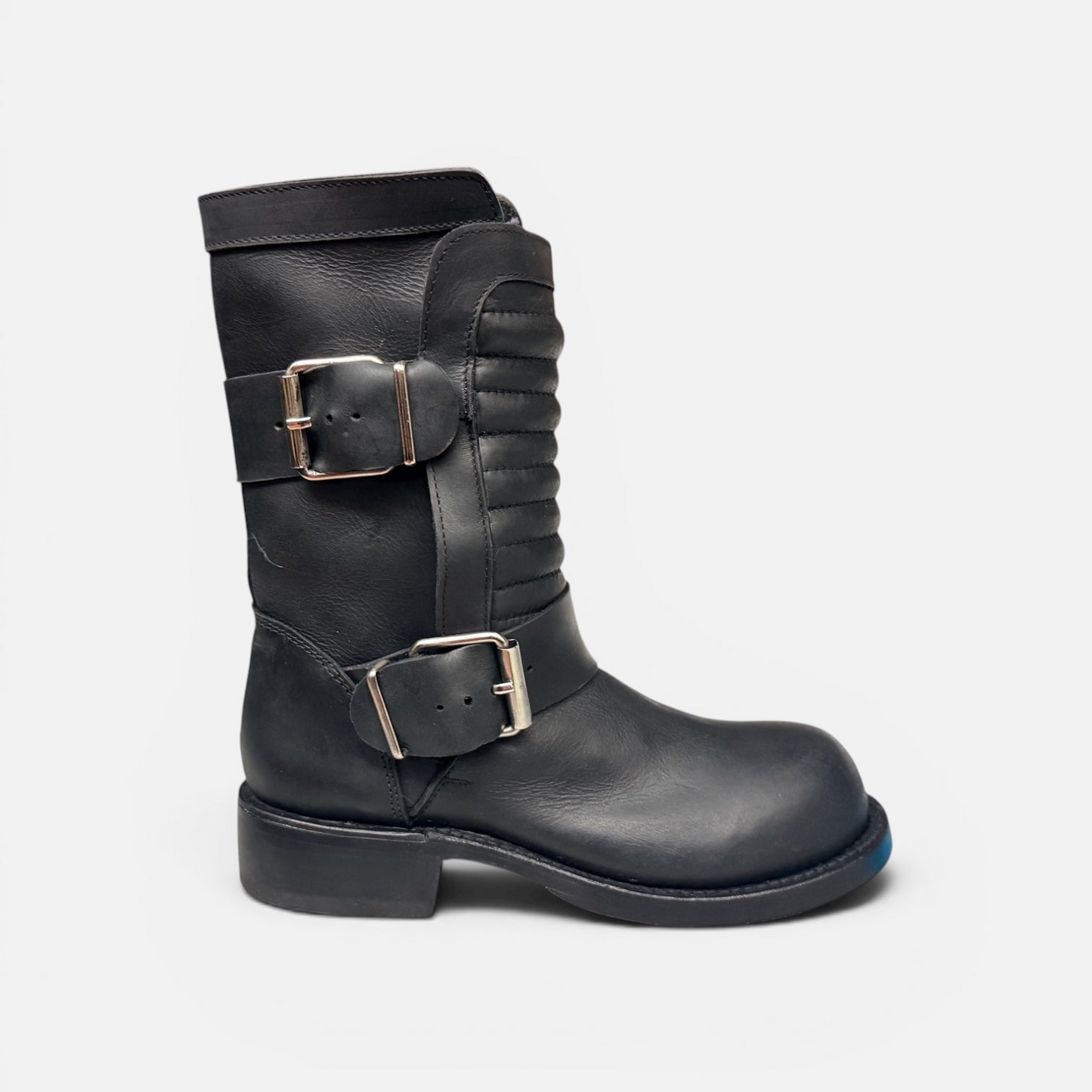 Black leather boot with silver buckles on a light gray background