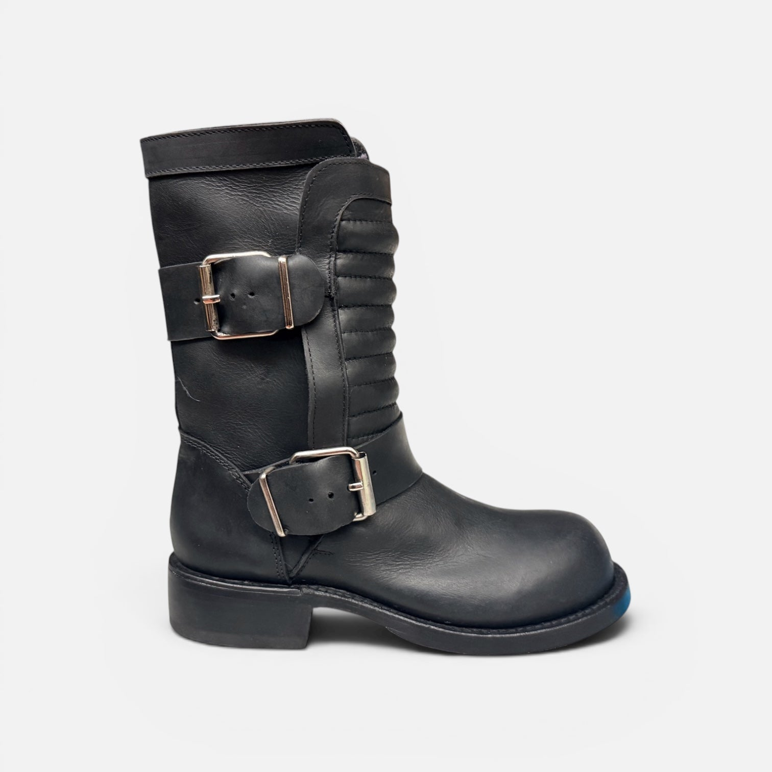 Black leather boot with silver buckles on a light gray background
