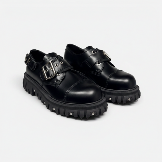 Black leather shoes with buckles on a light gray background