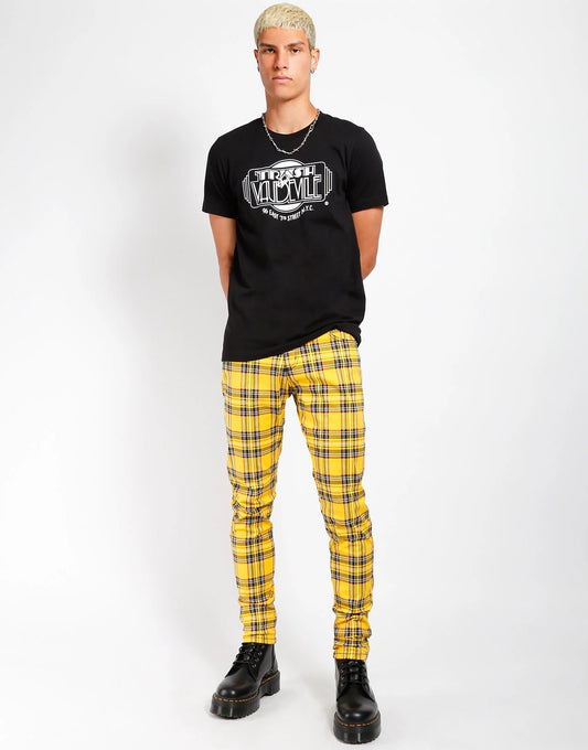 Person wearing a black t-shirt with a graphic design and yellow plaid pants on a white background