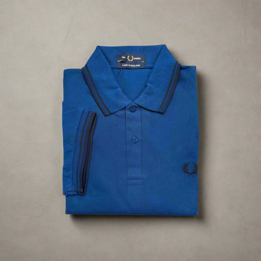 Folded blue polo shirt with brand logo on a beige background