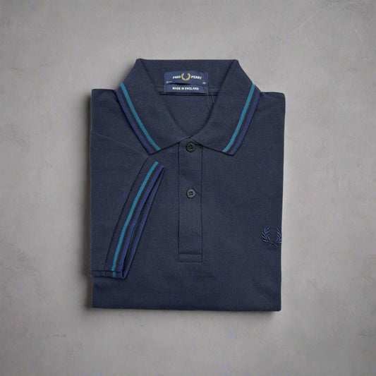 Folded navy polo shirt with blue trim on a white background